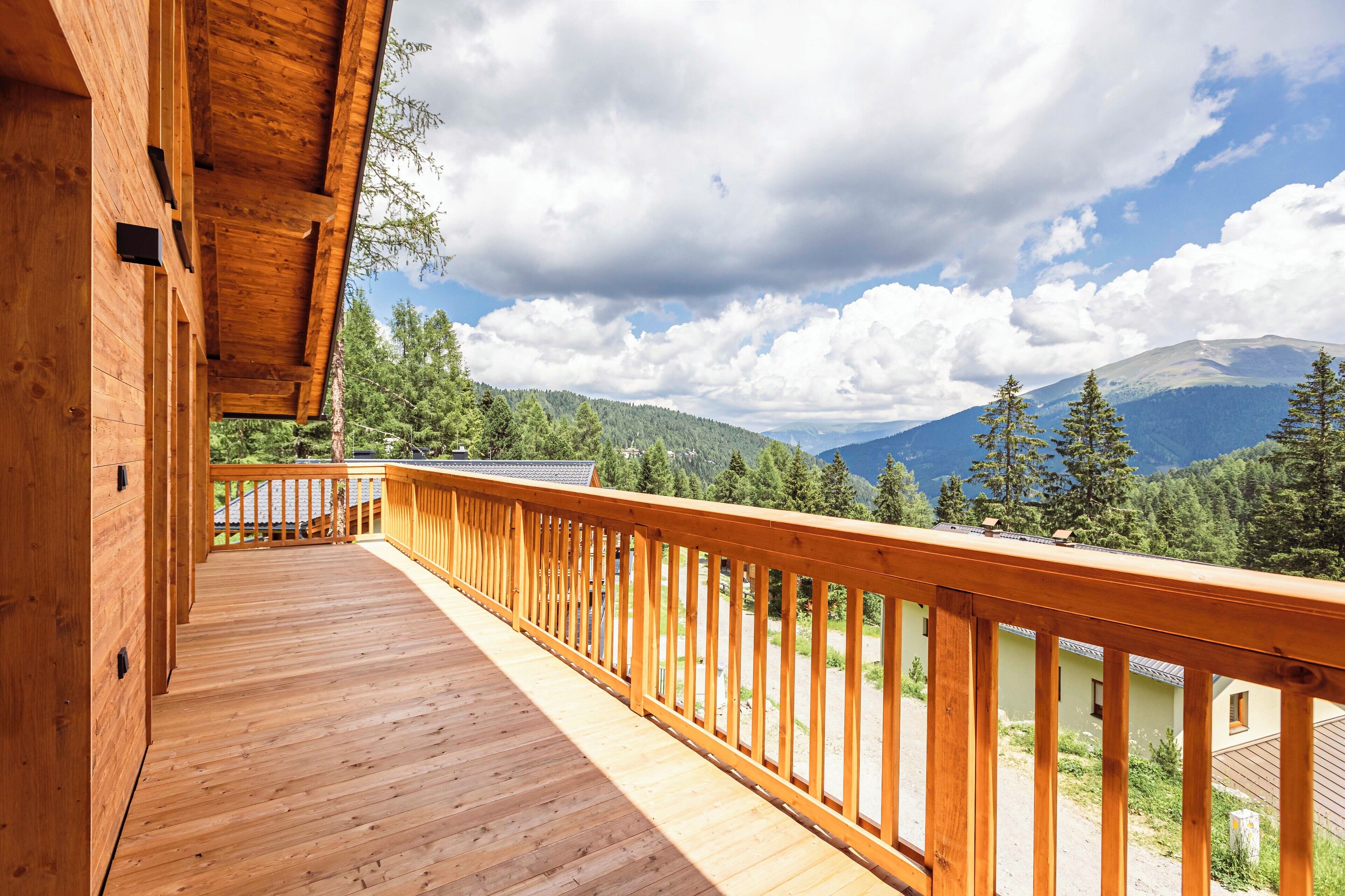 A wooden deck with a railing overlooking a mountainous landscape.
