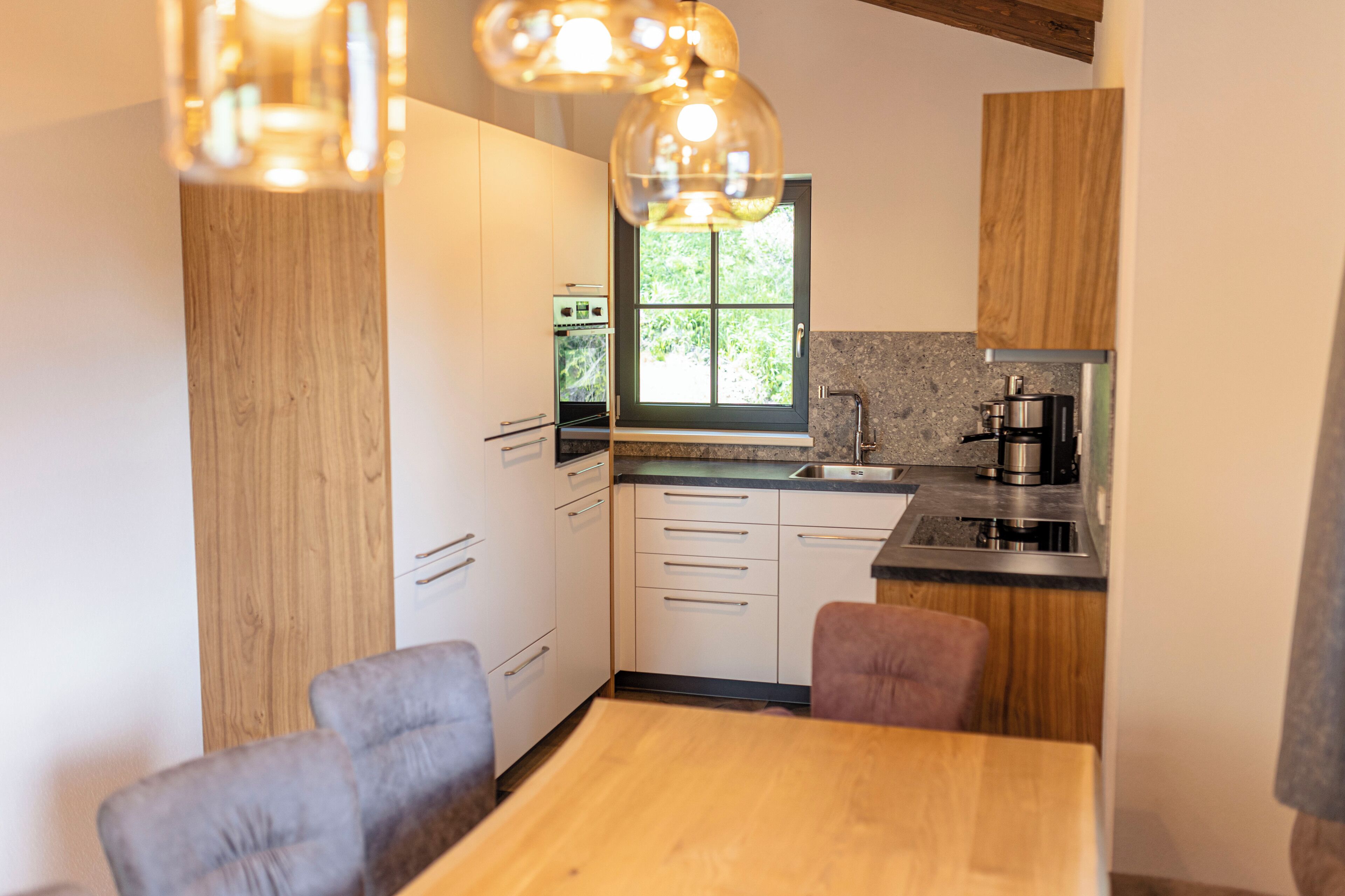 A modern kitchen with wooden cabinets, a window, and a dining area with a table and chairs.