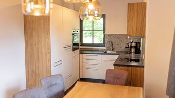 A modern kitchen with wooden cabinets, a window, and a dining area with a table and chairs.