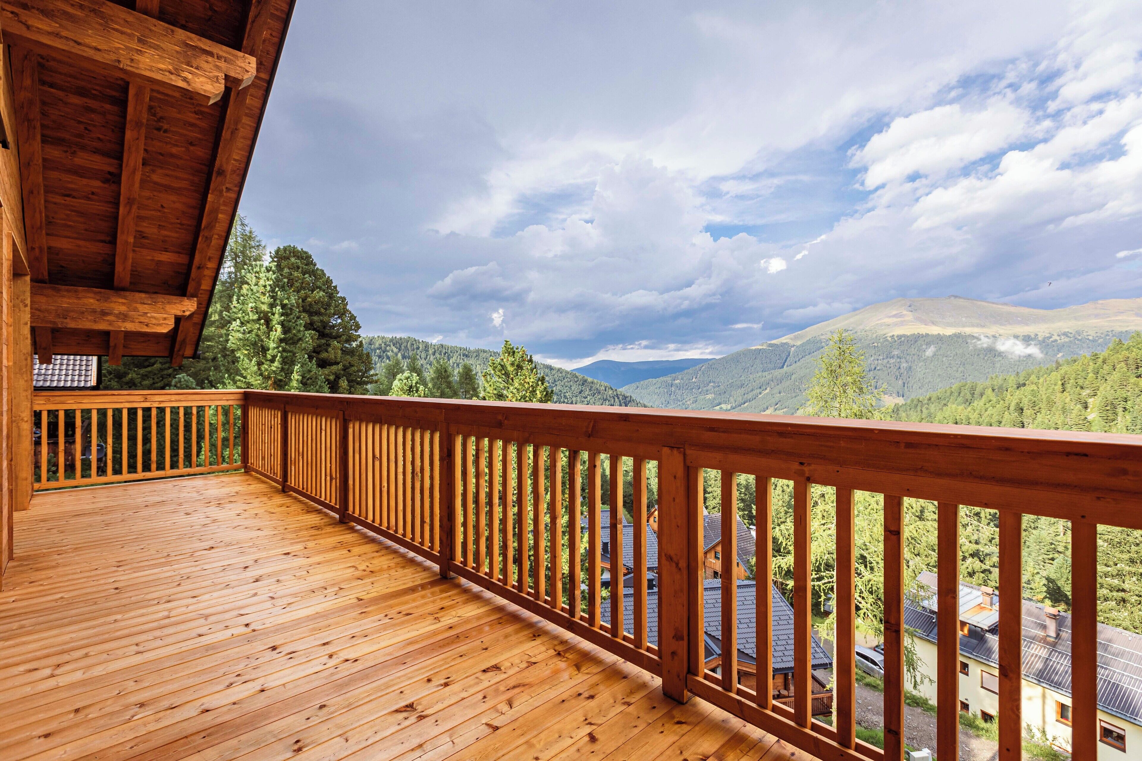 Una terraza de madera con barandilla que da a un paisaje montañoso.