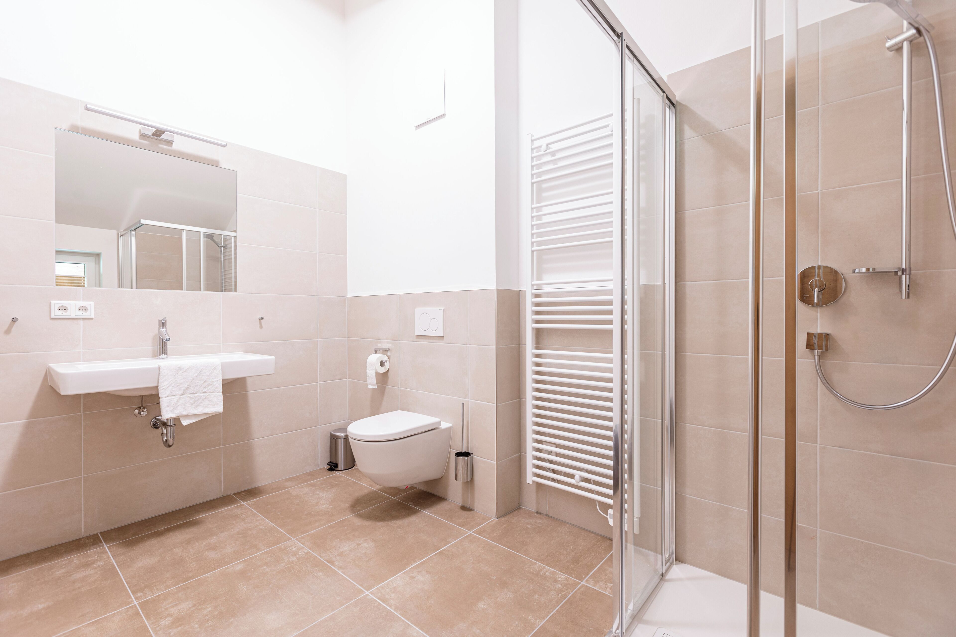 A modern bathroom with a glass-enclosed shower, a white sink, and a toilet.