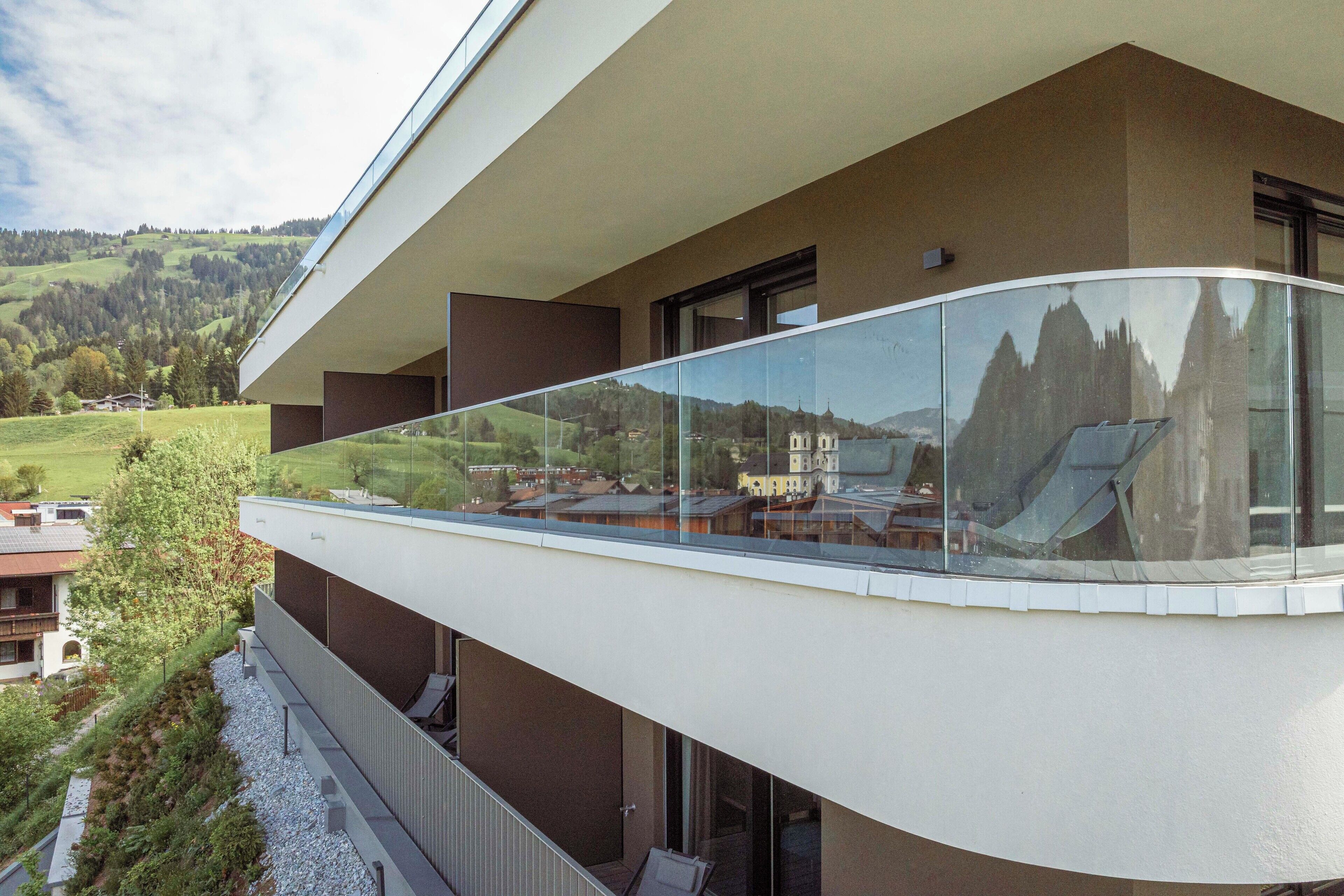 A modern building with a glass balcony overlooking a scenic landscape.
