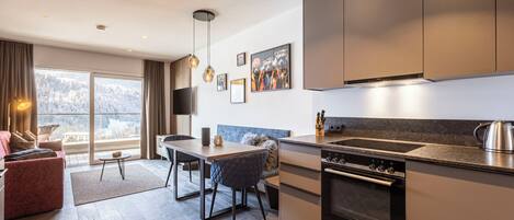 A modern kitchen with a built-in oven and a dining area with a table and chairs.