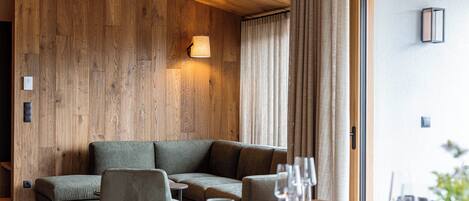 Un interior moderno con una pared de madera, un sofá, una mesa de comedor con platos y vasos, y una lámpara.