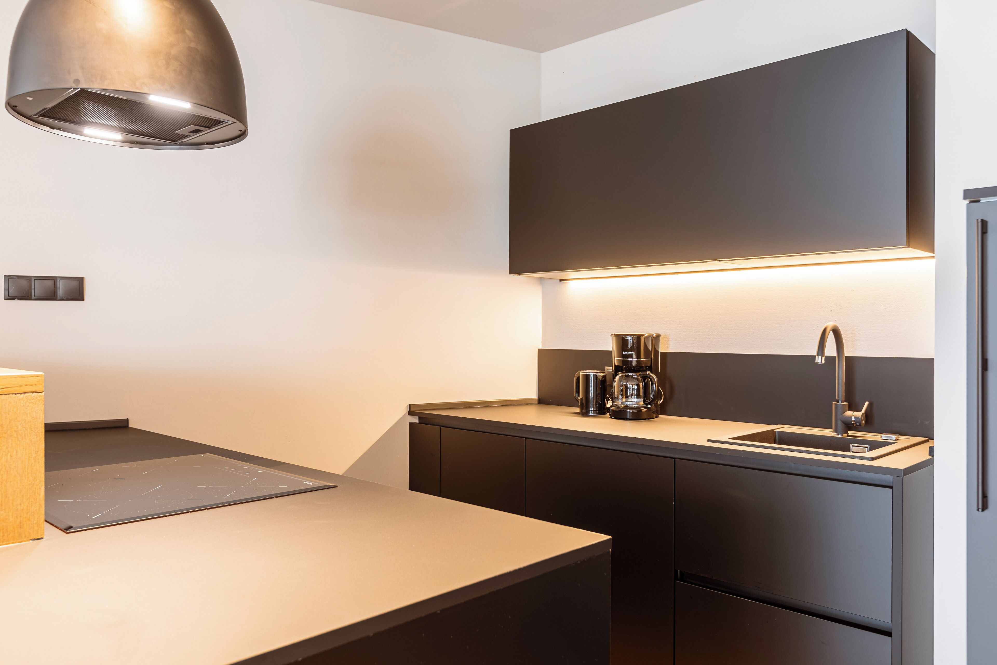 Una cocina moderna con estufa integrada, cafetera y lavabo.