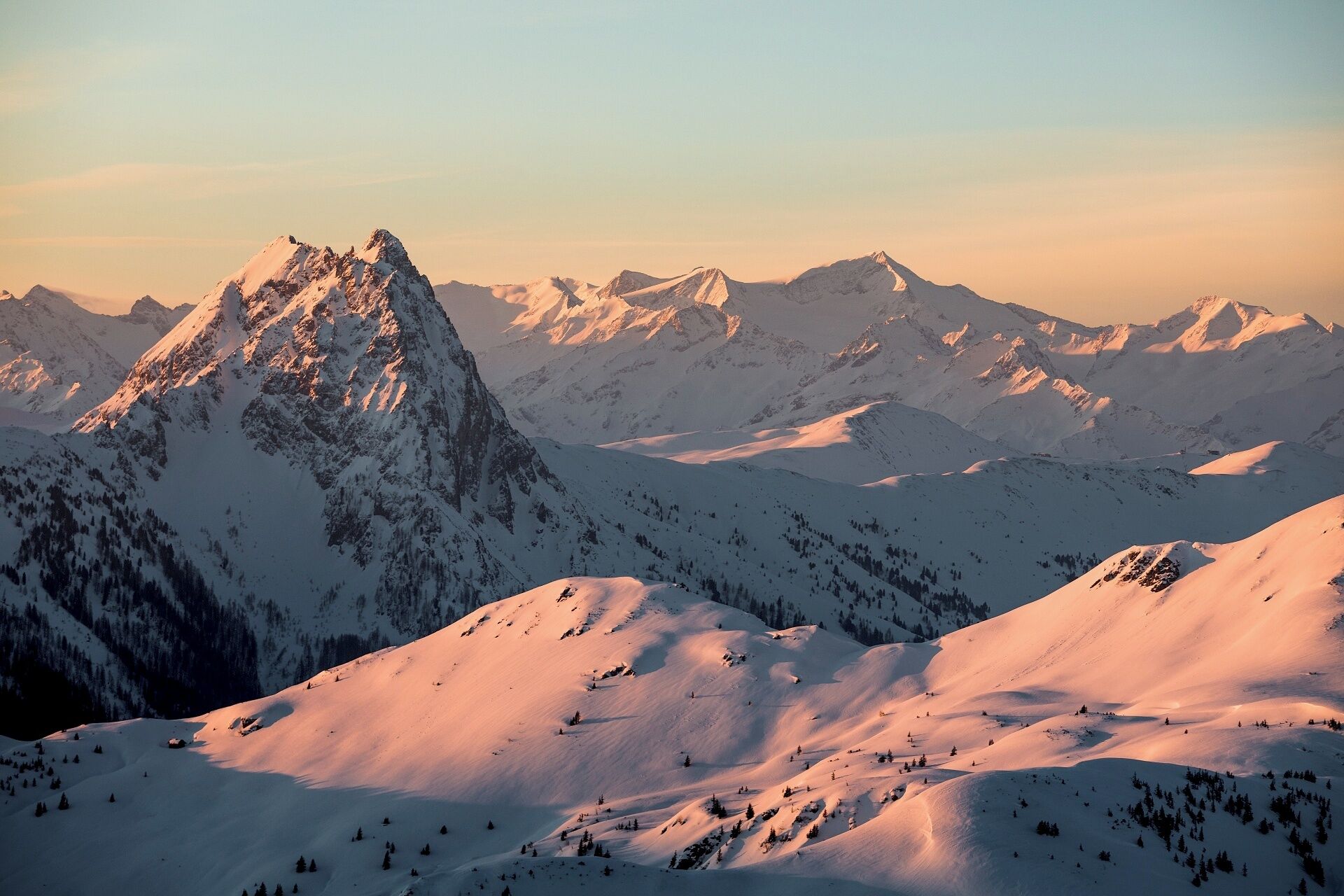 A snow-covered mountain range with a prominent peak in the foreground and a clear sky.