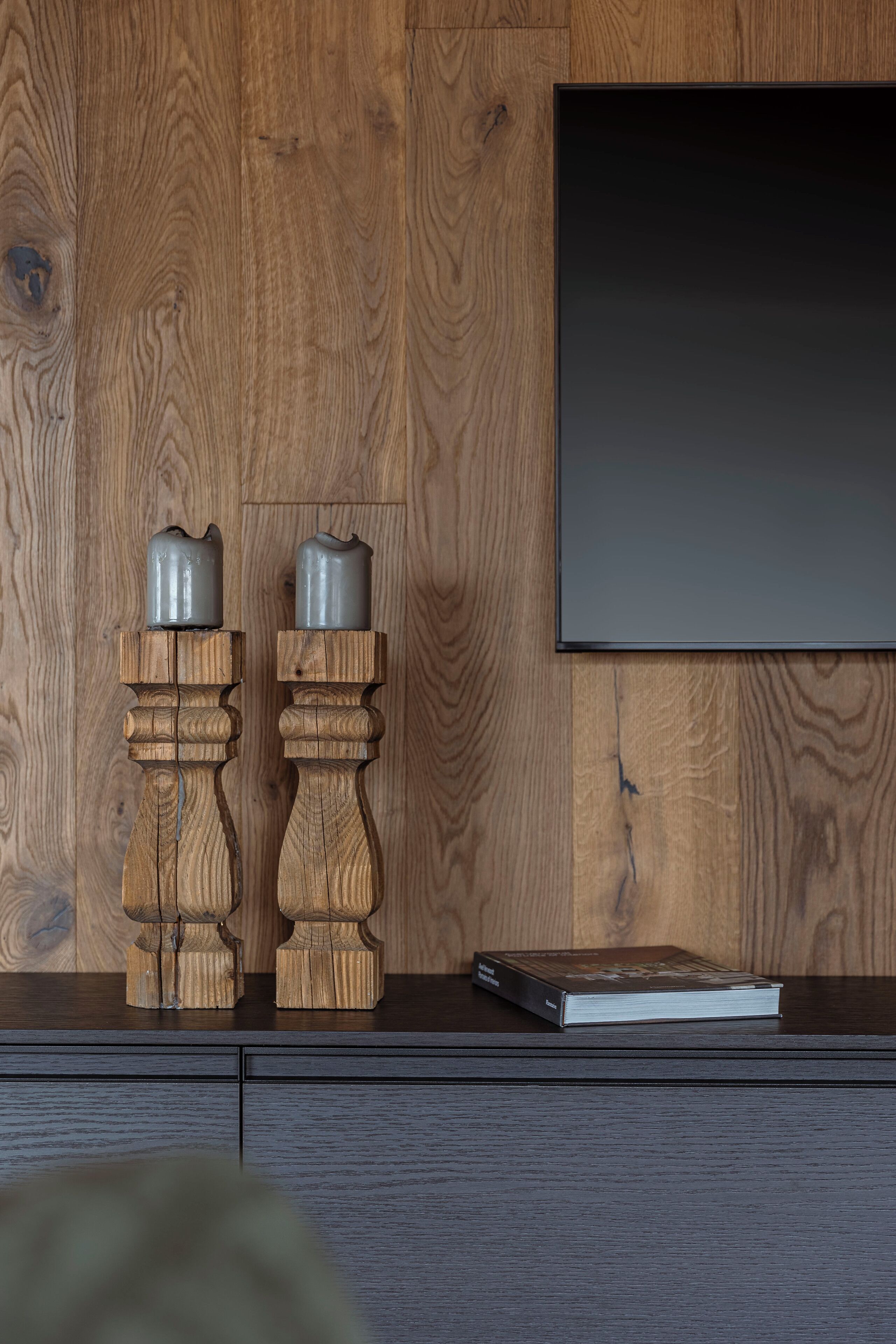 Eine Holzwand mit einem flachbildfernseher, der über einem dunklen Holzschrank angebracht ist.