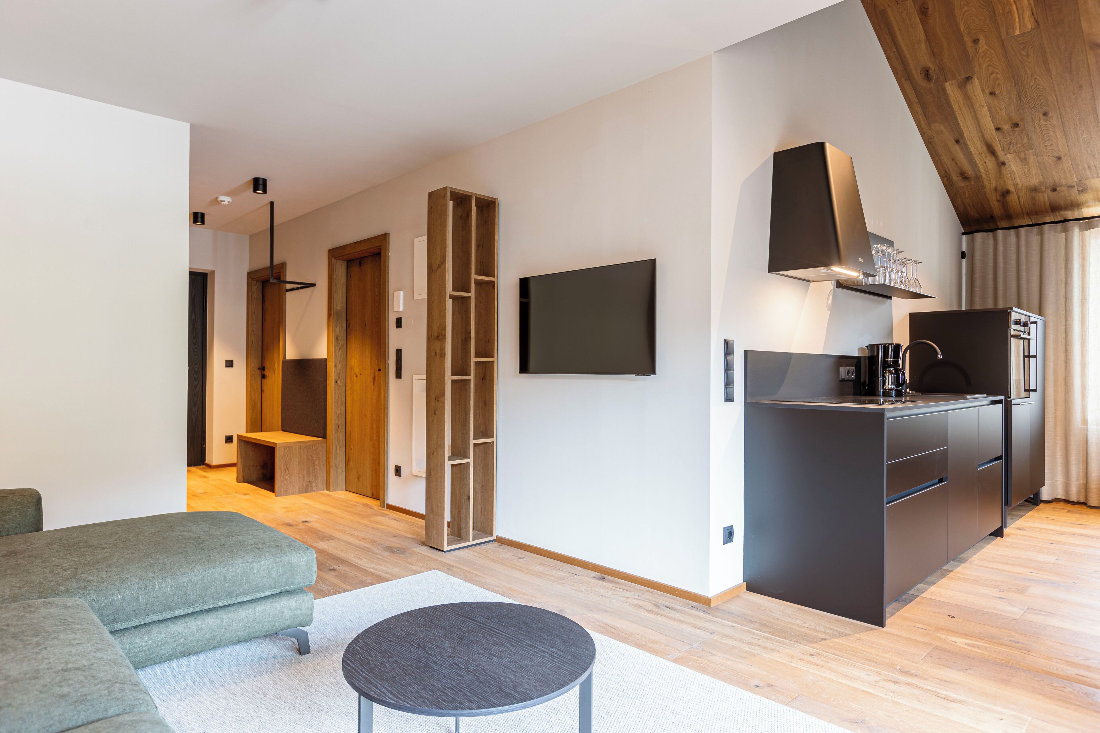 A modern kitchen with a built-in stove, a flat-screen TV, and a wooden ceiling.
