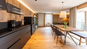 Une cuisine moderne dotée d’un plan de travail en bois, d’une machine à café et d’un four encastré. On y trouve également un coin repas avec une table et des chaises en bois, ainsi qu’un banc.