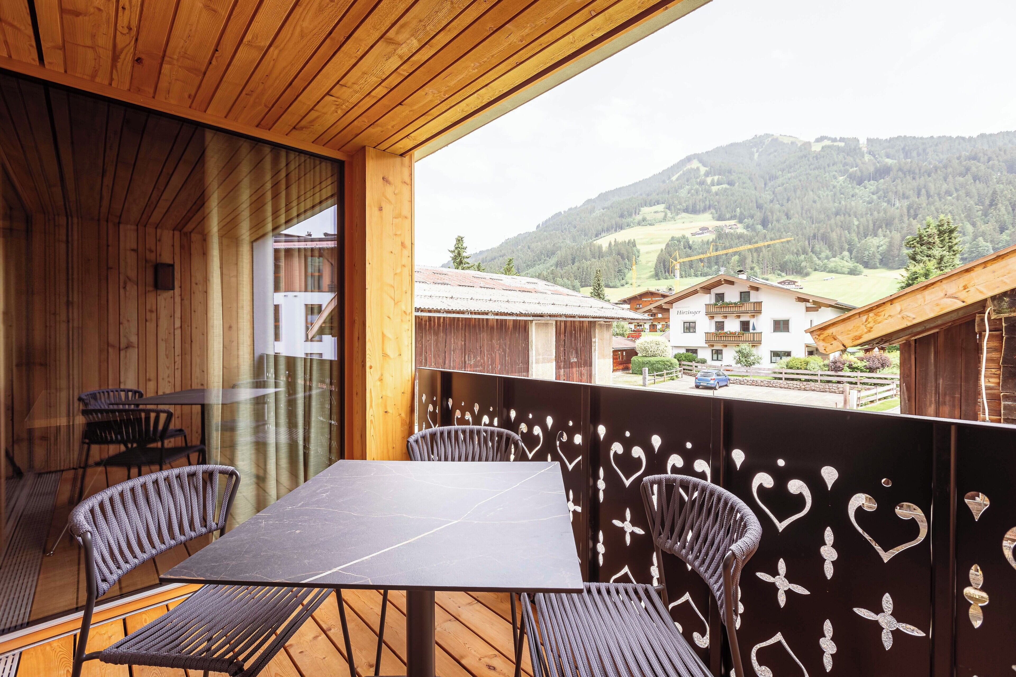 A wooden deck with a table and chairs, overlooking a mountainous landscape.