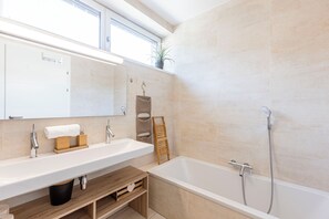 A modern bathroom with a large bathtub, a double sink vanity, and a mirror above the sink. - Naturpark Chalets Lambrecht (Sankt Lambrecht)