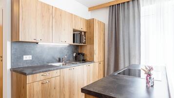 Een moderne keuken met houten kastjes, een ingebouwde magnetron en een groot aanrecht.