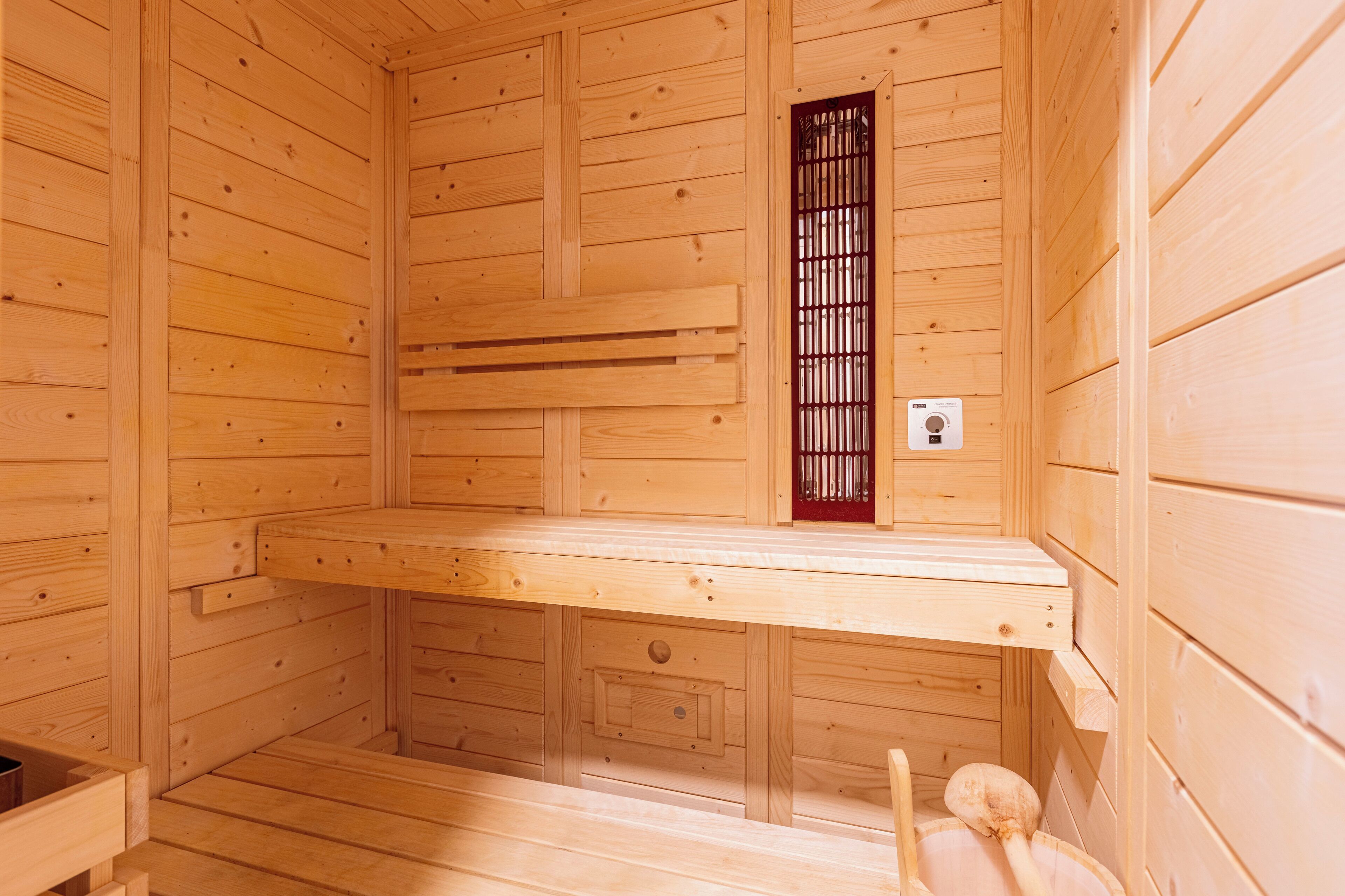 Una sauna de madera con bancos, una ventana y un panel de control.