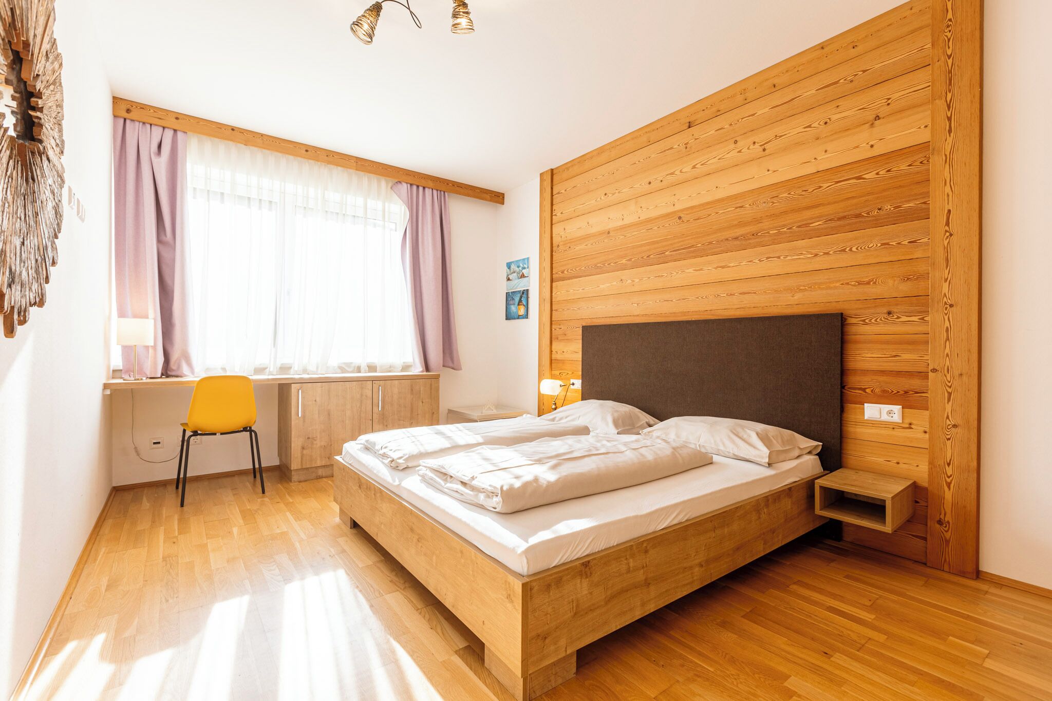 A bedroom with a wooden bed, a desk, and a chair.
