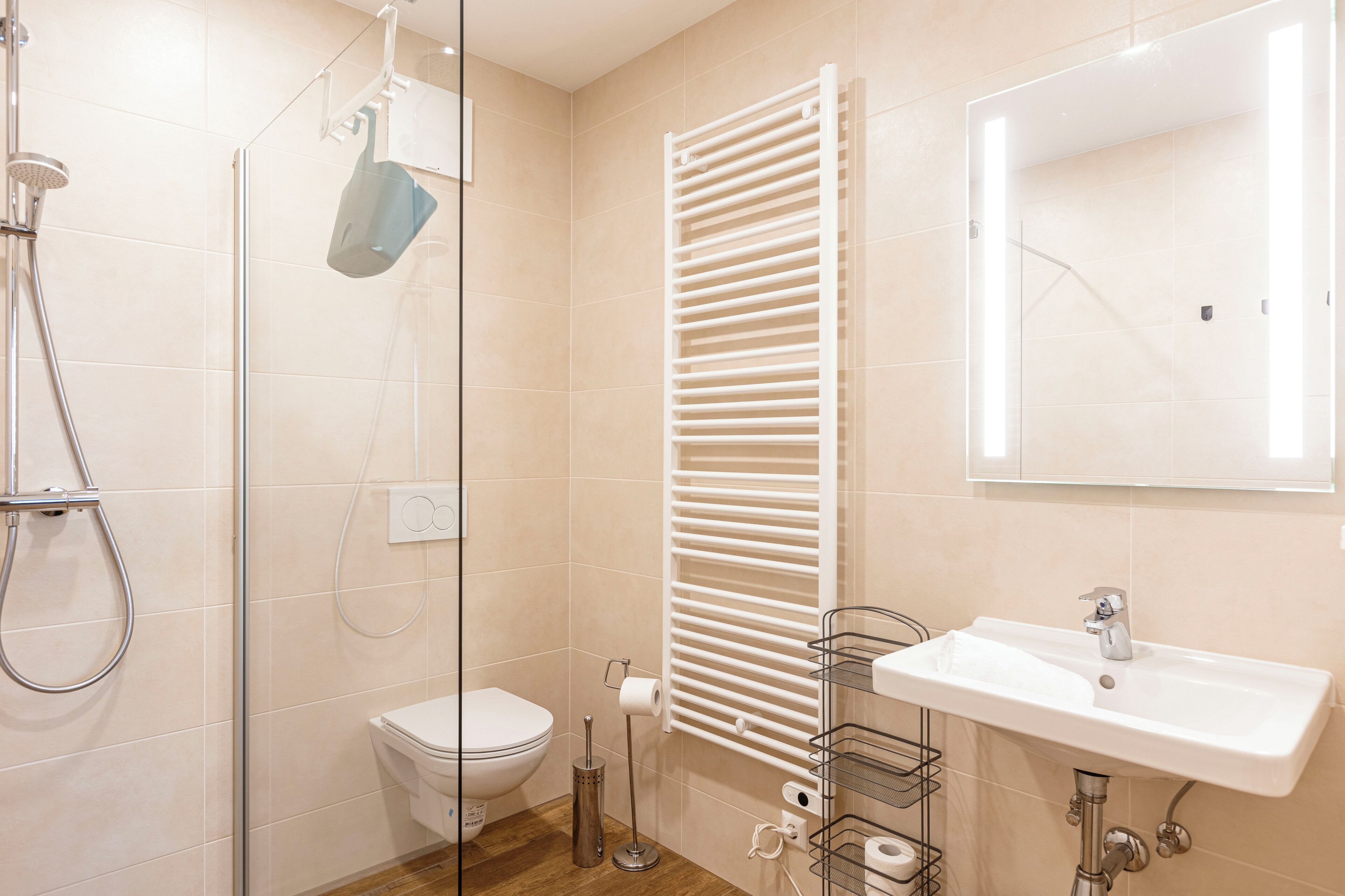 Een moderne badkamer met een glazen douchecabine, een wit toilet, een handdoekhouder en een wastafel met een spiegel erboven.