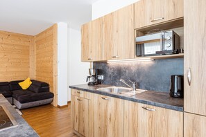 A compact kitchen with wooden cabinets, a built-in microwave, and a coffee maker. - Naturpark Chalets Lambrecht (Sankt Lambrecht)