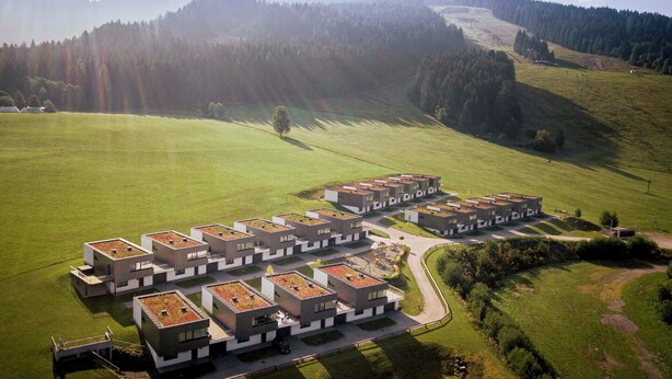 A modern residential complex with multiple buildings, green roofs, and a surrounding grassy area. - Naturpark Chalets Lambrecht (Sankt Lambrecht)