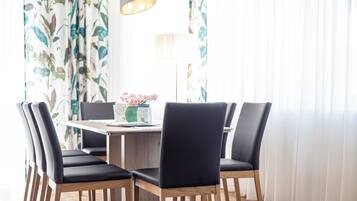 Un comedor con una mesa de madera y sillas negras, un jarrón con flores y una lámpara.