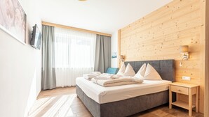 A modern bedroom with a grey bed, wooden headboard, and a nightstand. - Naturpark Chalets Lambrecht (Sankt Lambrecht)