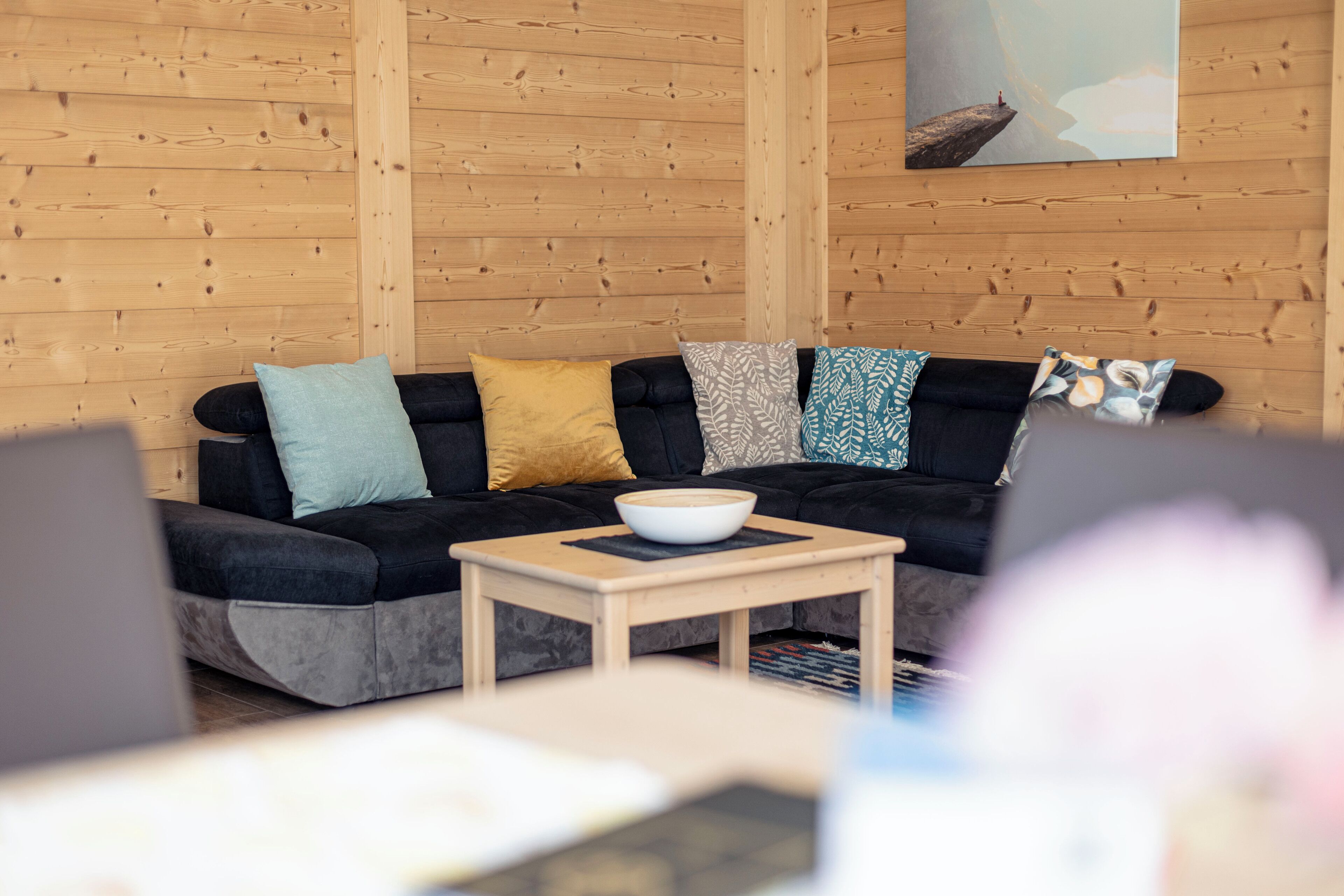 A cozy living area with a black sofa, a wooden coffee table, and a bowl on it.