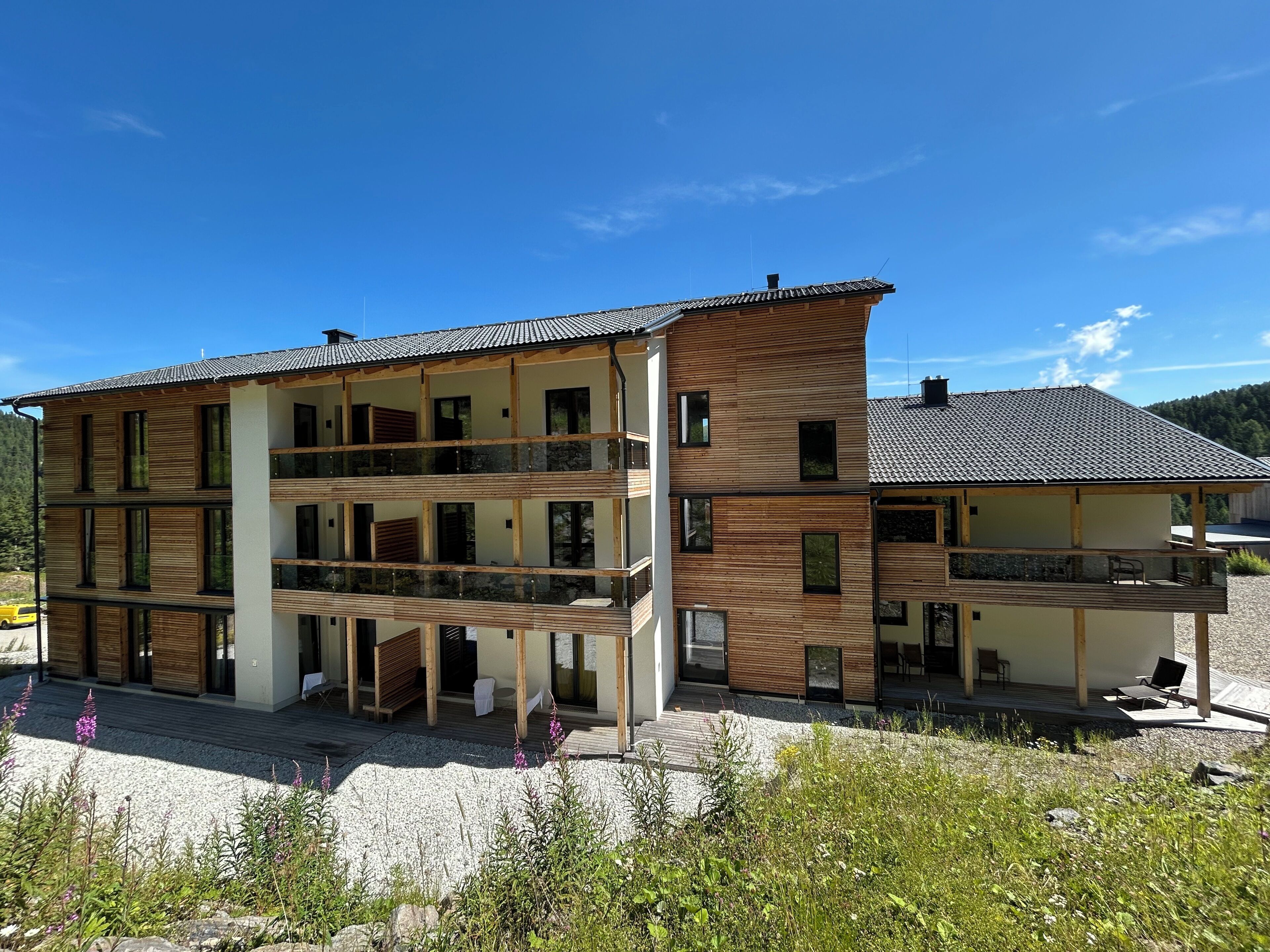 A multi-story building with balconies, a covered entrance, and a gravel driveway.