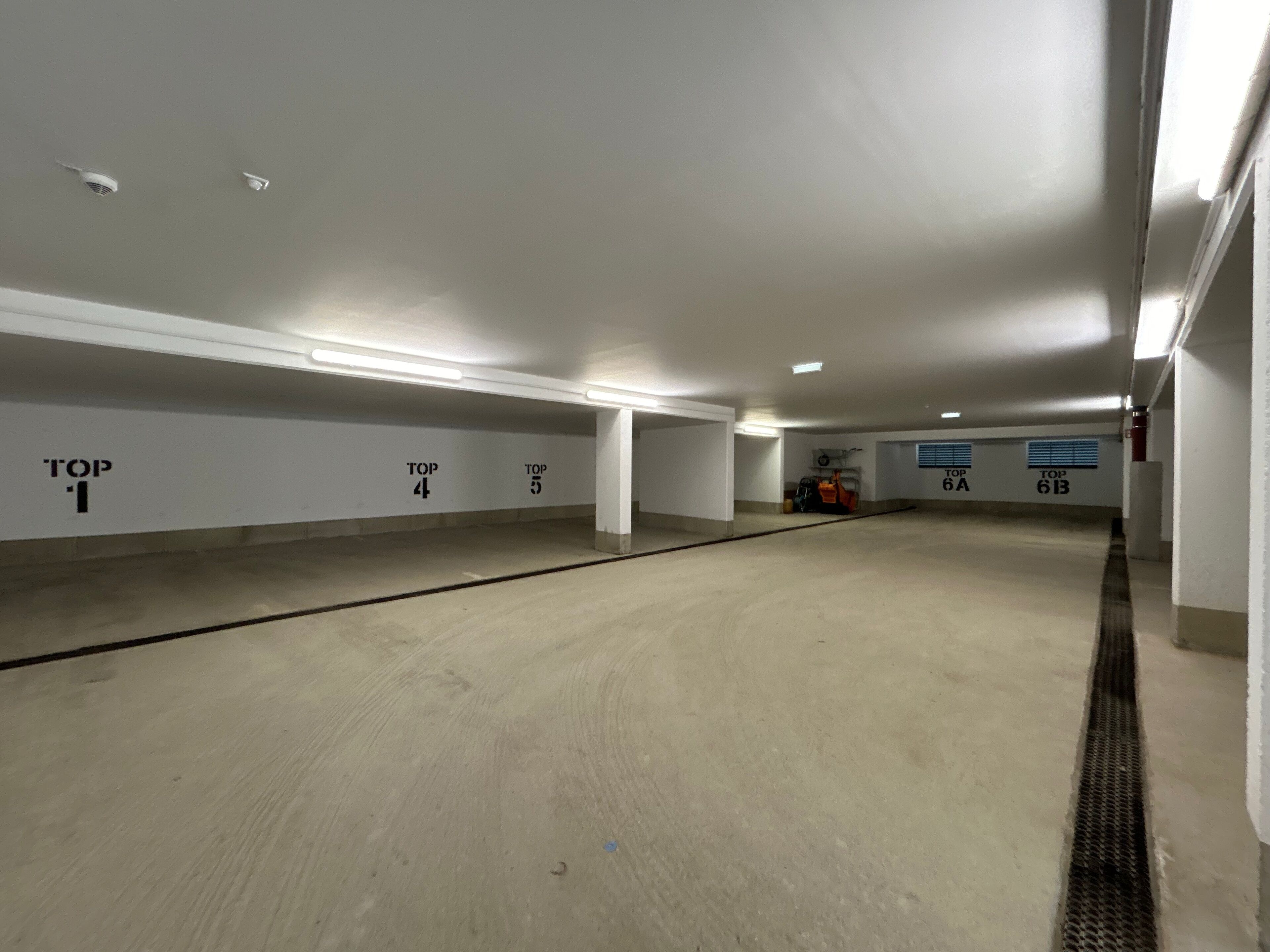 Un parking souterrain vide, avec des places de stationnement numérotées et un éclairage au plafond.