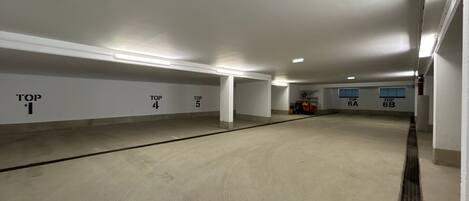 An empty parking garage with numbered parking spaces and overhead lighting.