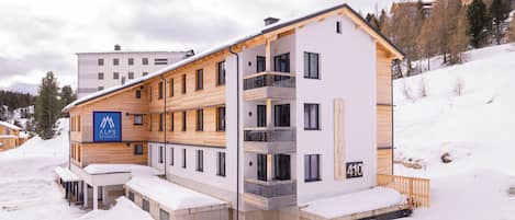 A multi-story hotel with a modern design, featuring balconies and a ski resort sign.