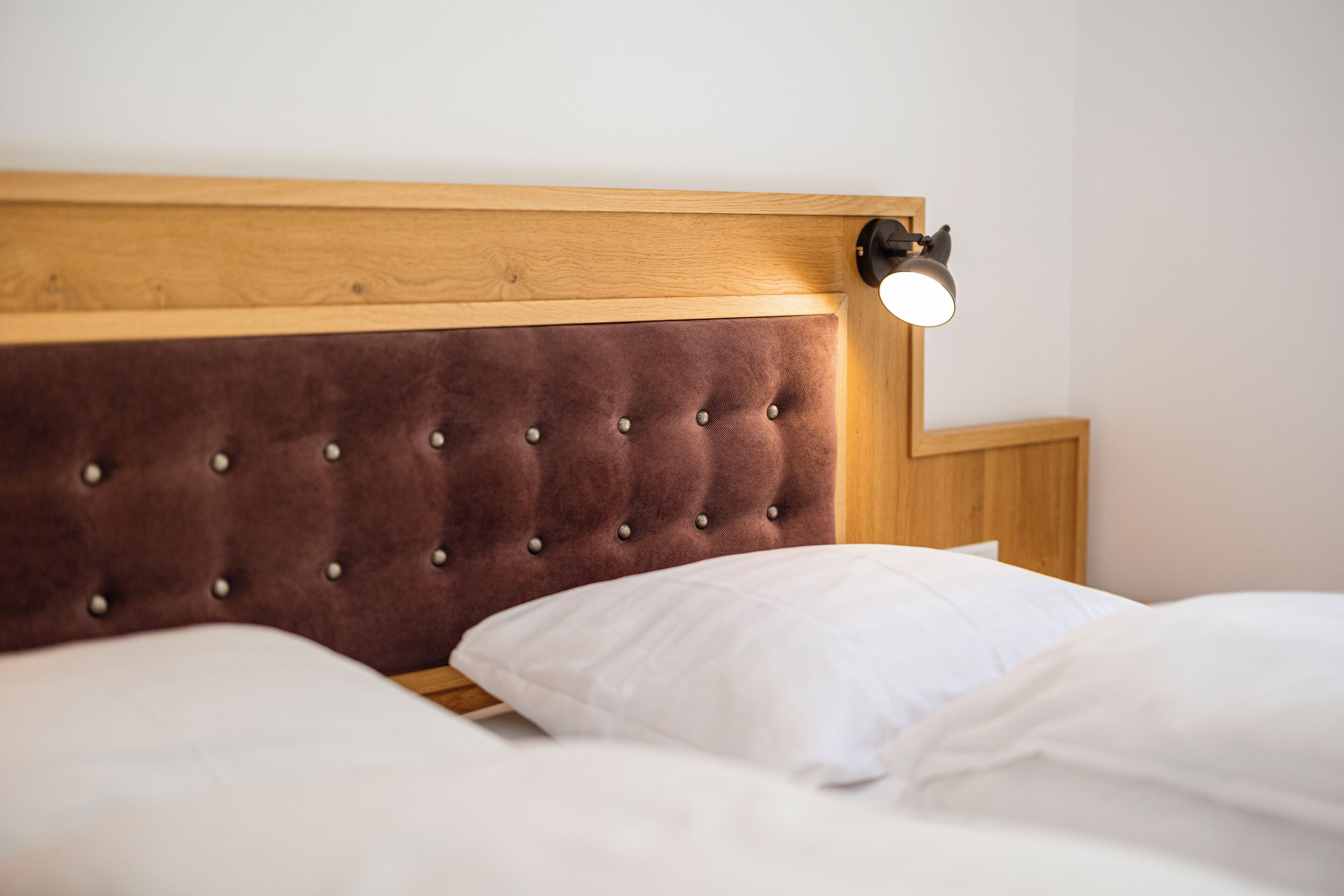A bed with a wooden headboard and a bedside lamp.