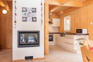 A modern kitchen with wooden walls, a built-in oven, and a microwave.