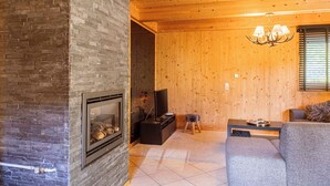 Un salon chaleureux avec une cheminée, un téléviseur et un coin salon confortable.