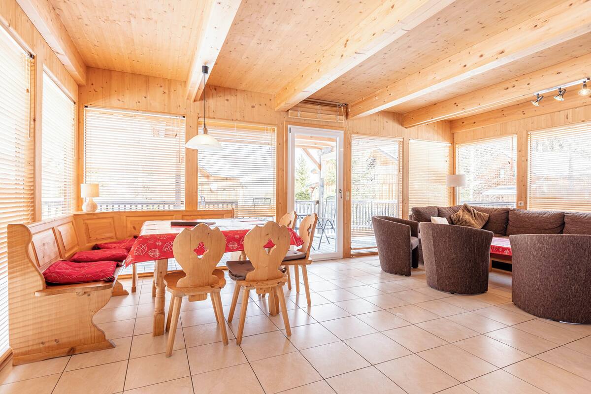 Interior de madera con comedor, sofá y sillas.