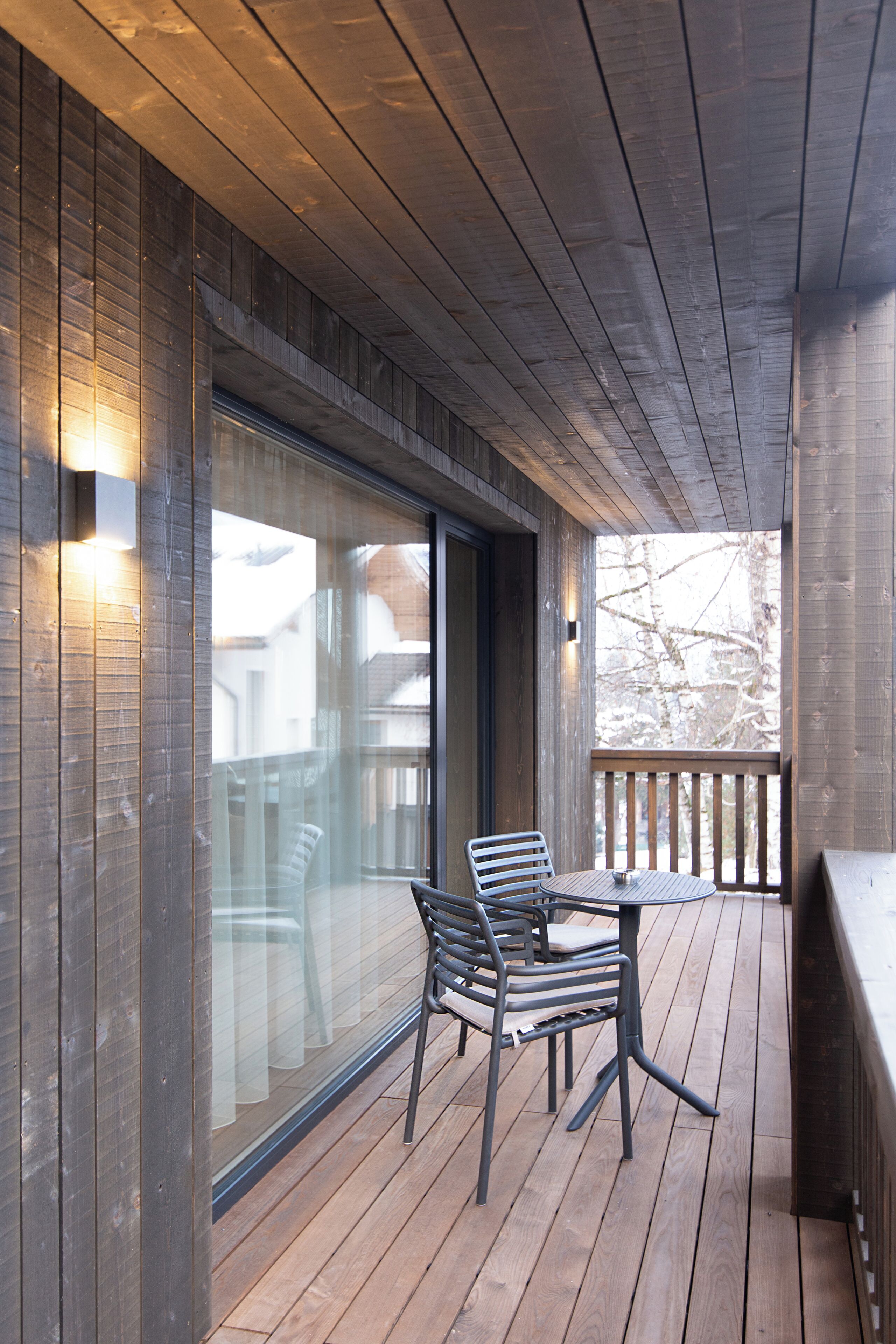 En træterrasse med en glasdør, der fører til en overdækket patio.