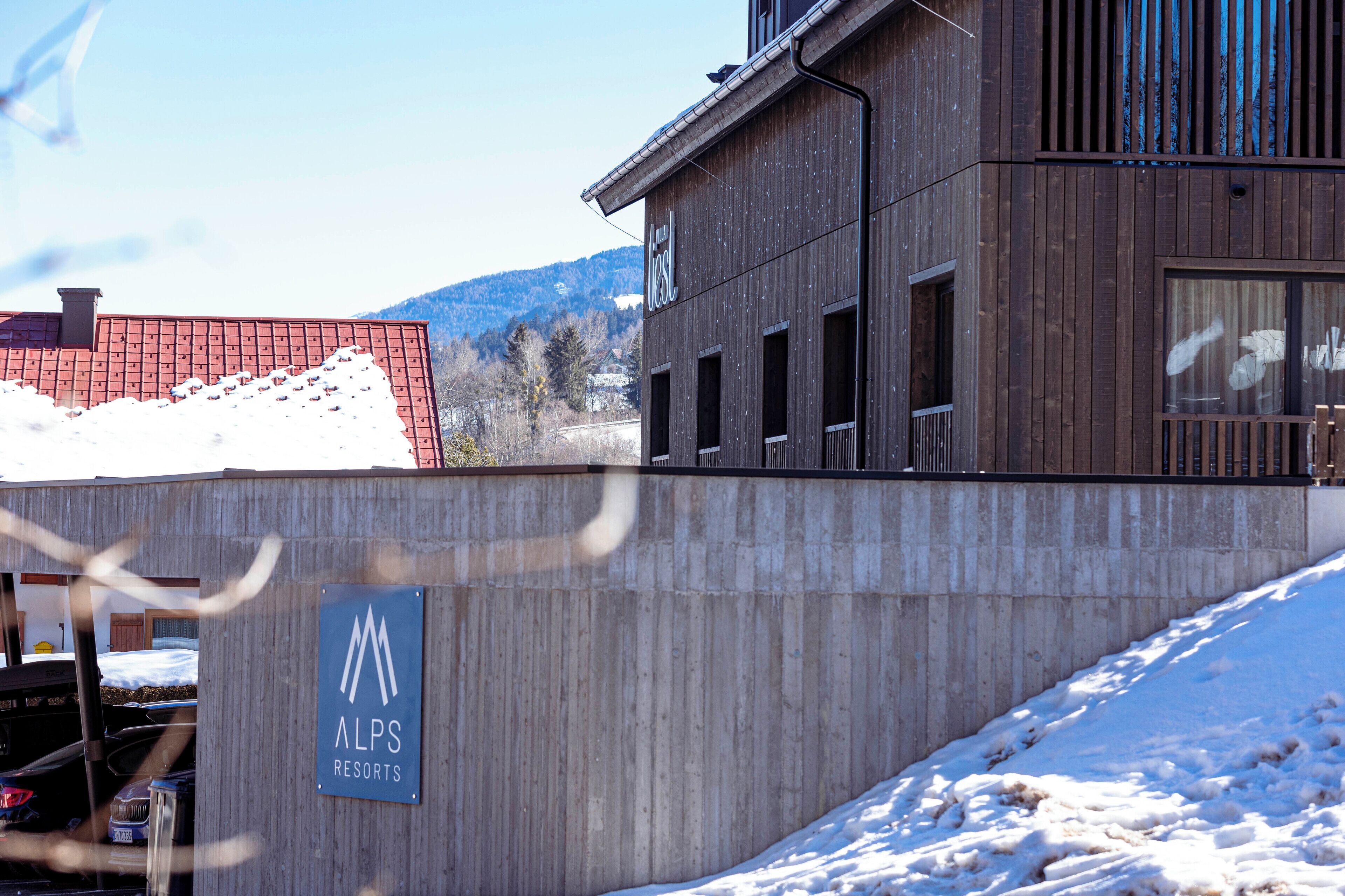 A building with a sign for 'ALPS RESORTS' and a snow-covered slope.