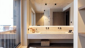 Een moderne badkamer met een groot raam, een dubbele wastafel en een kruk.