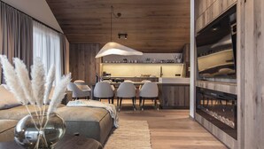 Een moderne woonkamer met een bank, een salontafel met een vaas, en een eethoek met stoelen, met een keuken op de achtergrond.