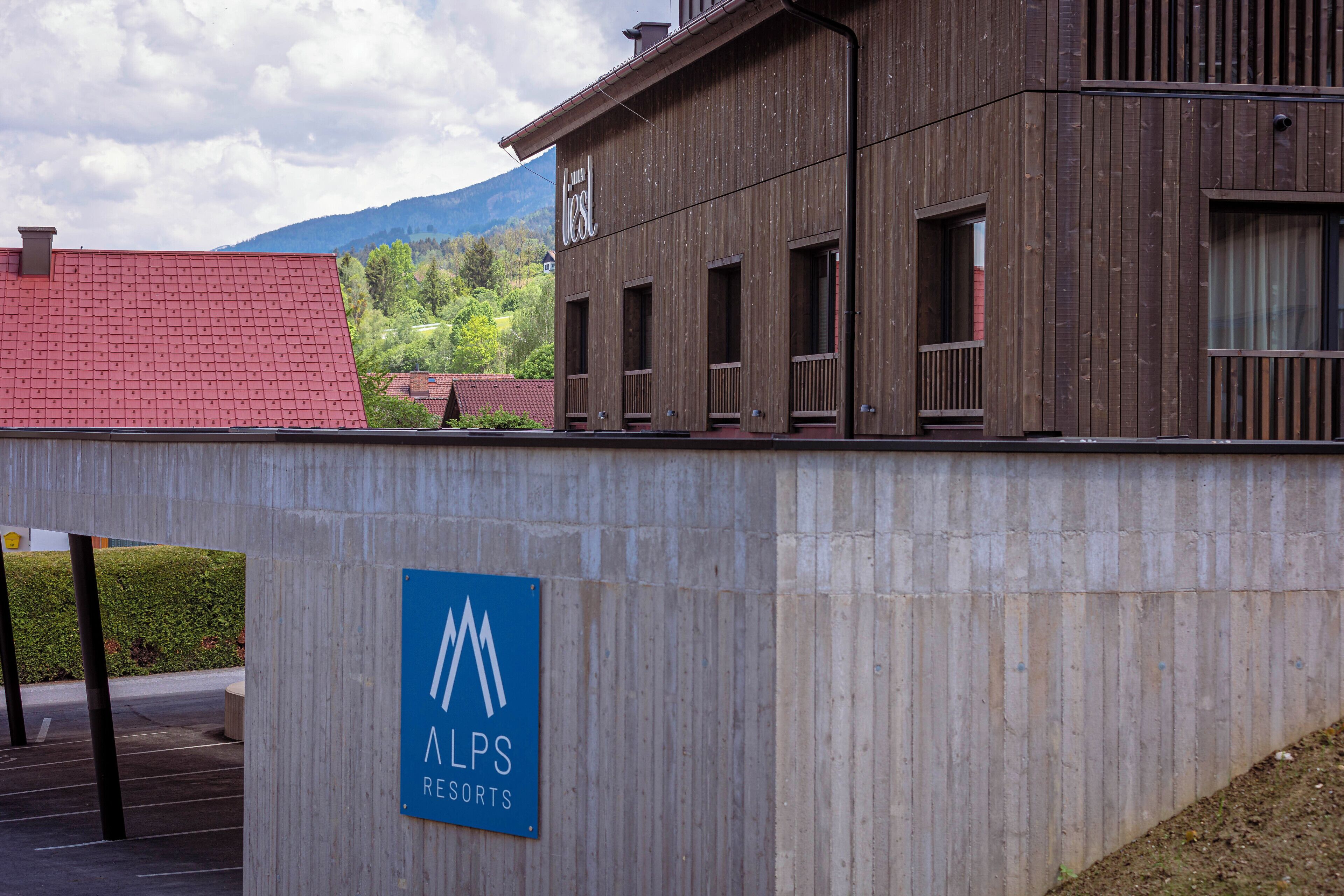 Un bâtiment arborant une enseigne « ALPS Resorts », caractérisé par un design moderne avec des panneaux en bois et de grandes fenêtres.