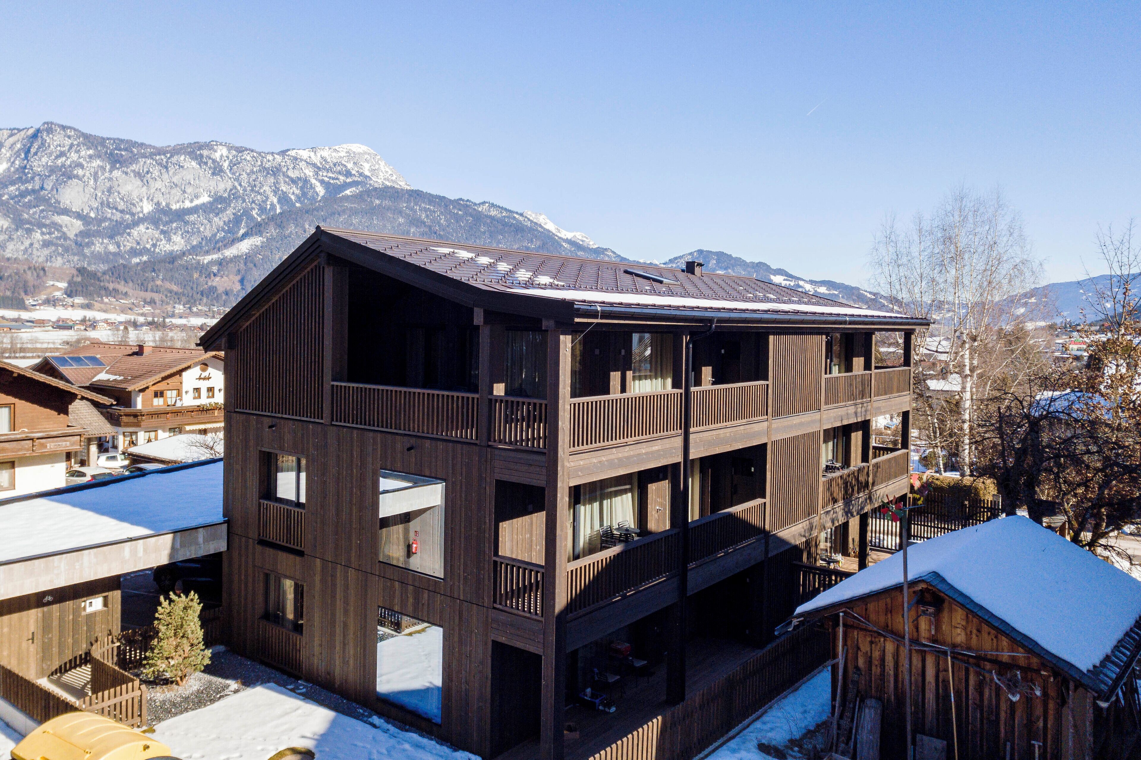 A multi-story wooden building with balconies, set against a mountainous backdrop.