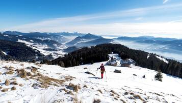 Une personne fait du ski sur une montagne enneigée, avec une vue sur des montagnes lointaines et un ciel dégagé.