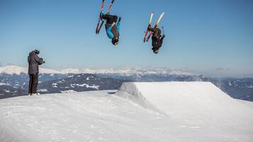 A snowy ski slope with a photographer capturing a skier in mid-air.