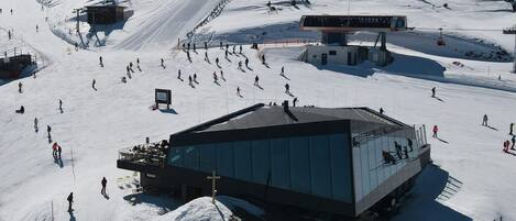 Un centro de esquí con un edificio moderno, telesillas y un paisaje cubierto de nieve.