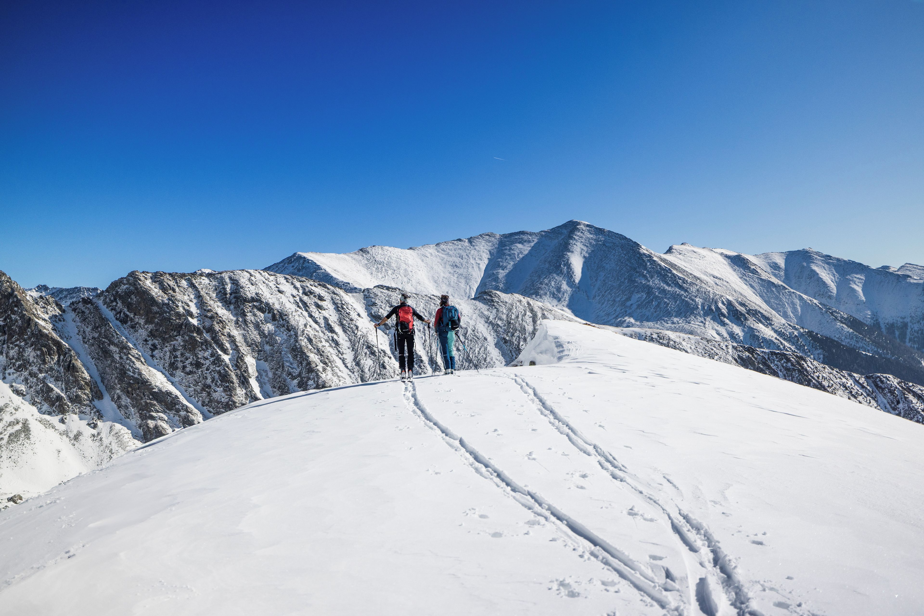 A snowy mountain landscape with two hikers.