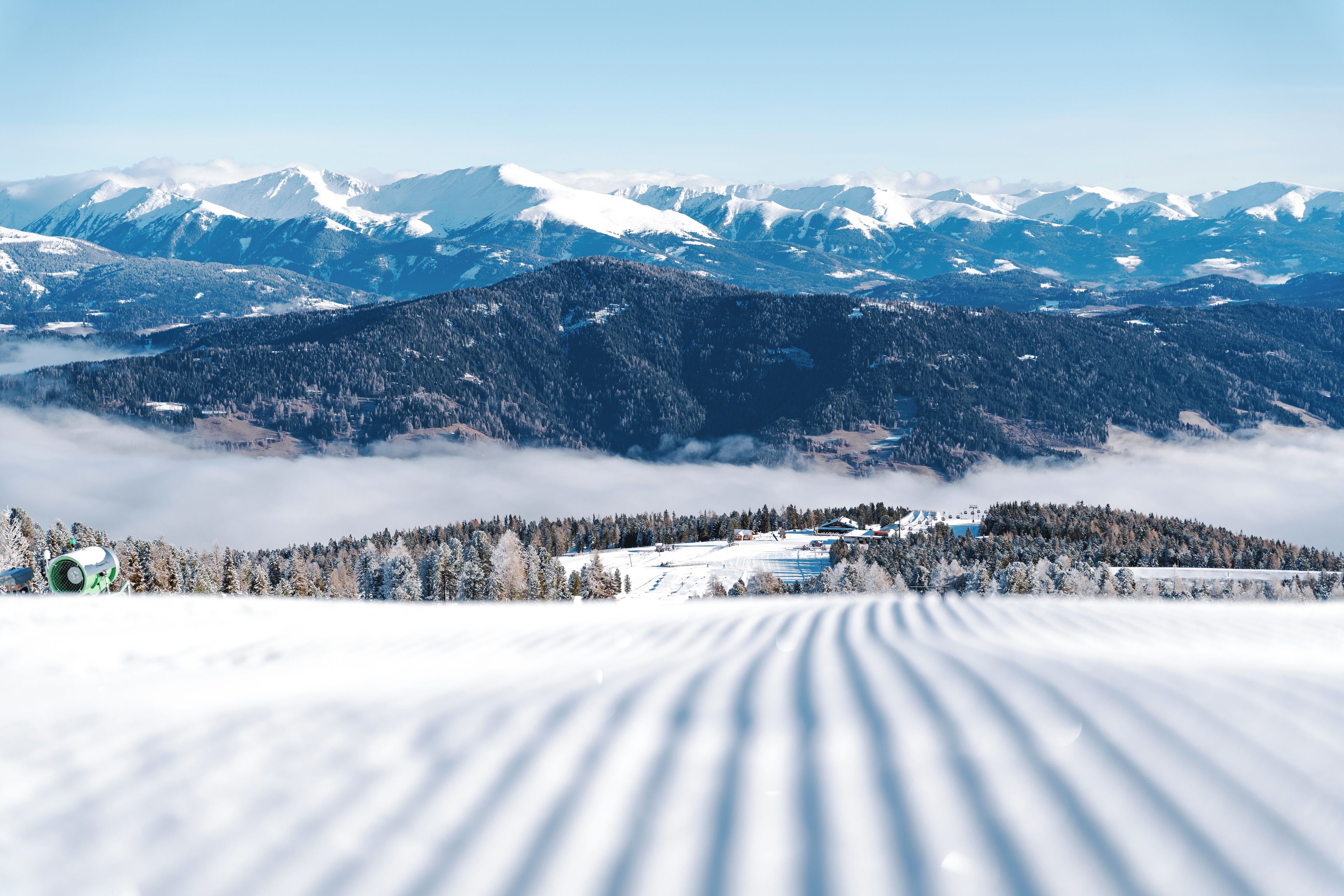 A snow-covered mountain landscape with a ski resort in the foreground.