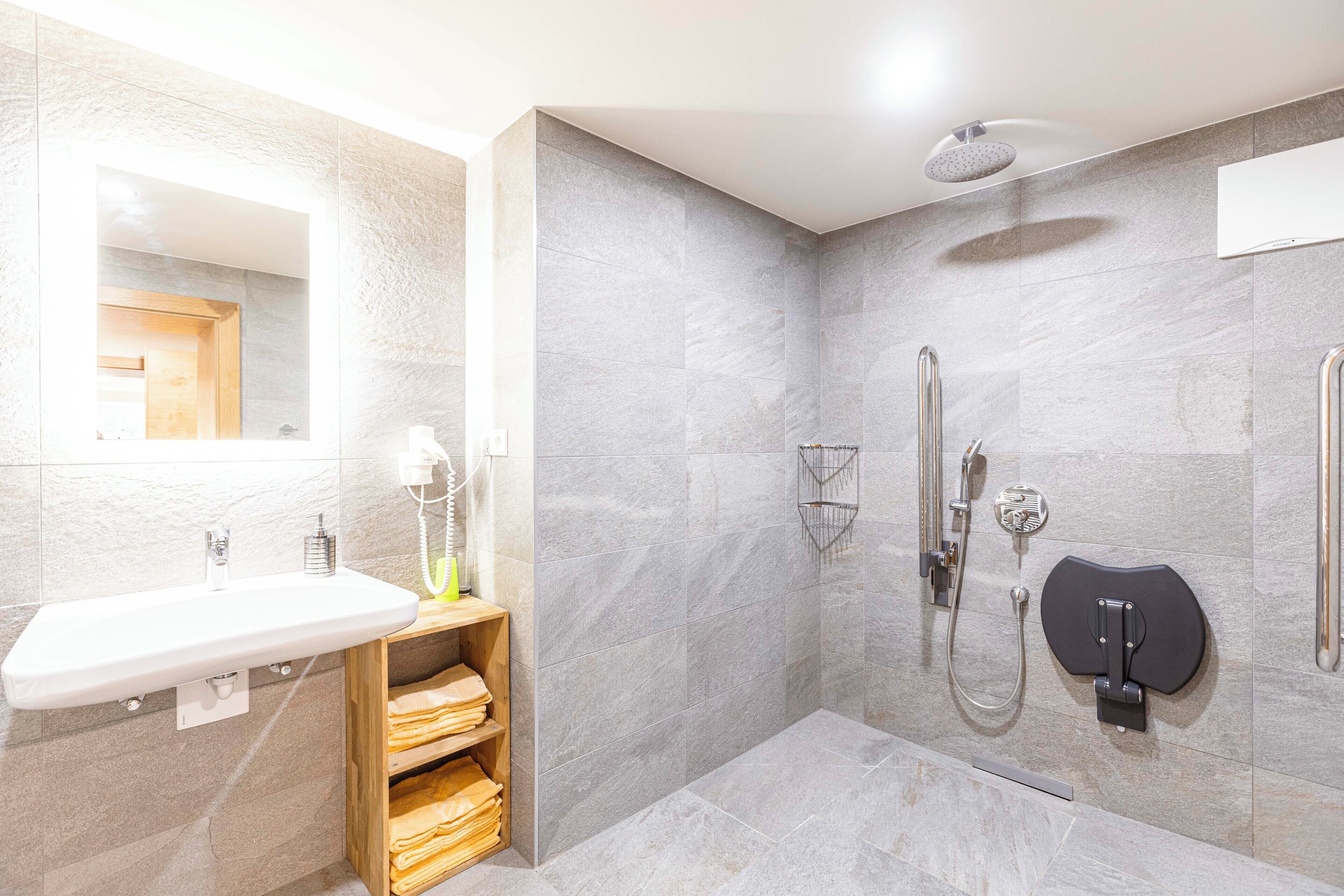 A modern bathroom with a built-in sink, a shower with a handheld showerhead, and a towel rack.