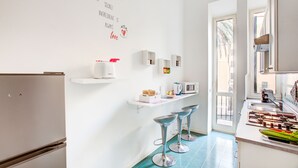 A modern kitchen with white cabinetry, a built-in microwave, and a countertop with bar stools.