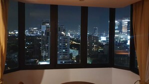 A room with a large window offering a nighttime city view. - Direct Rooms at Omni Complex Nana (Bangkok)
