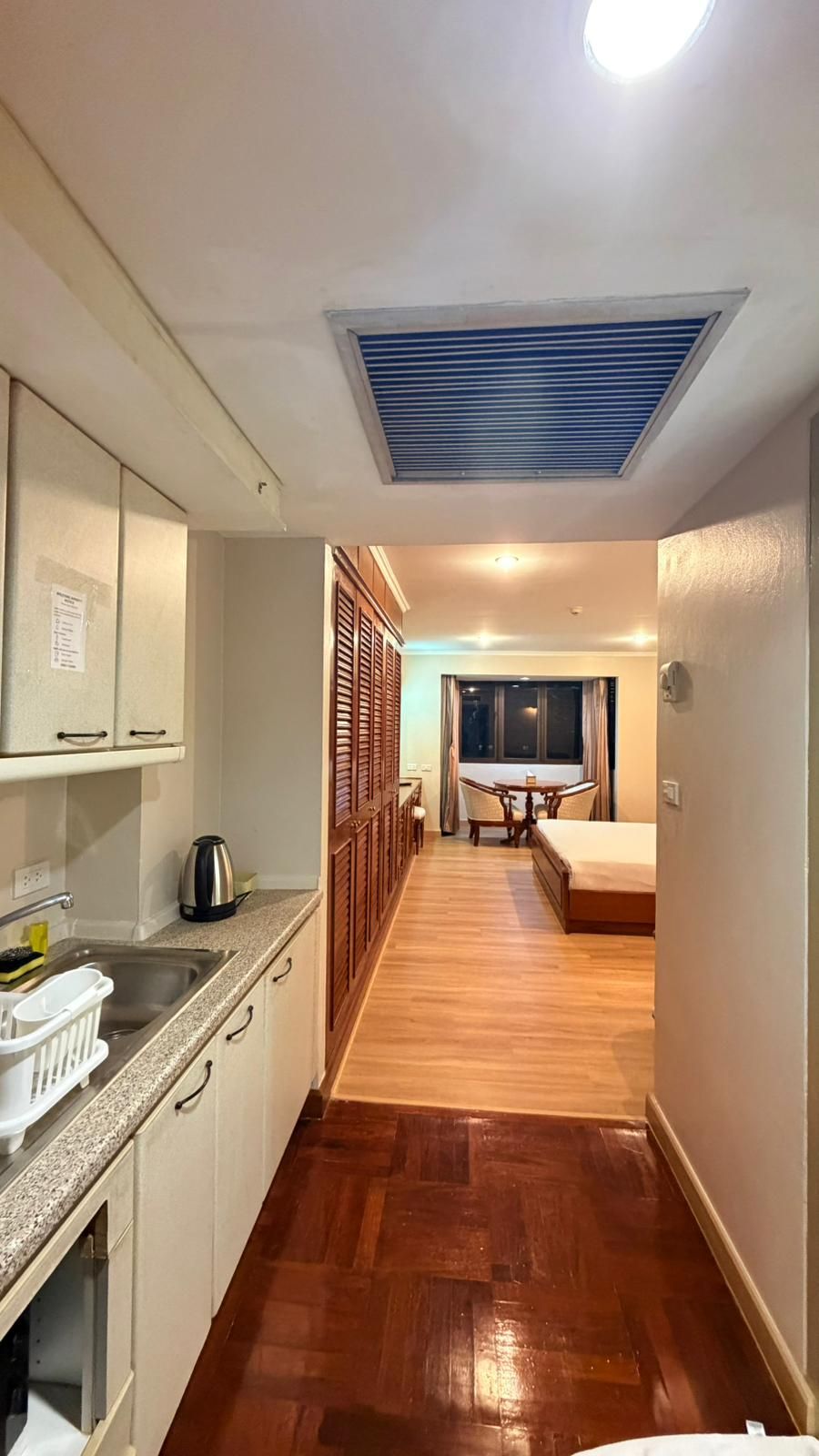 Une chambre d’hôtel de taille réduite, dotée d’une kitchenette, d’un coin repas et d’un lit.