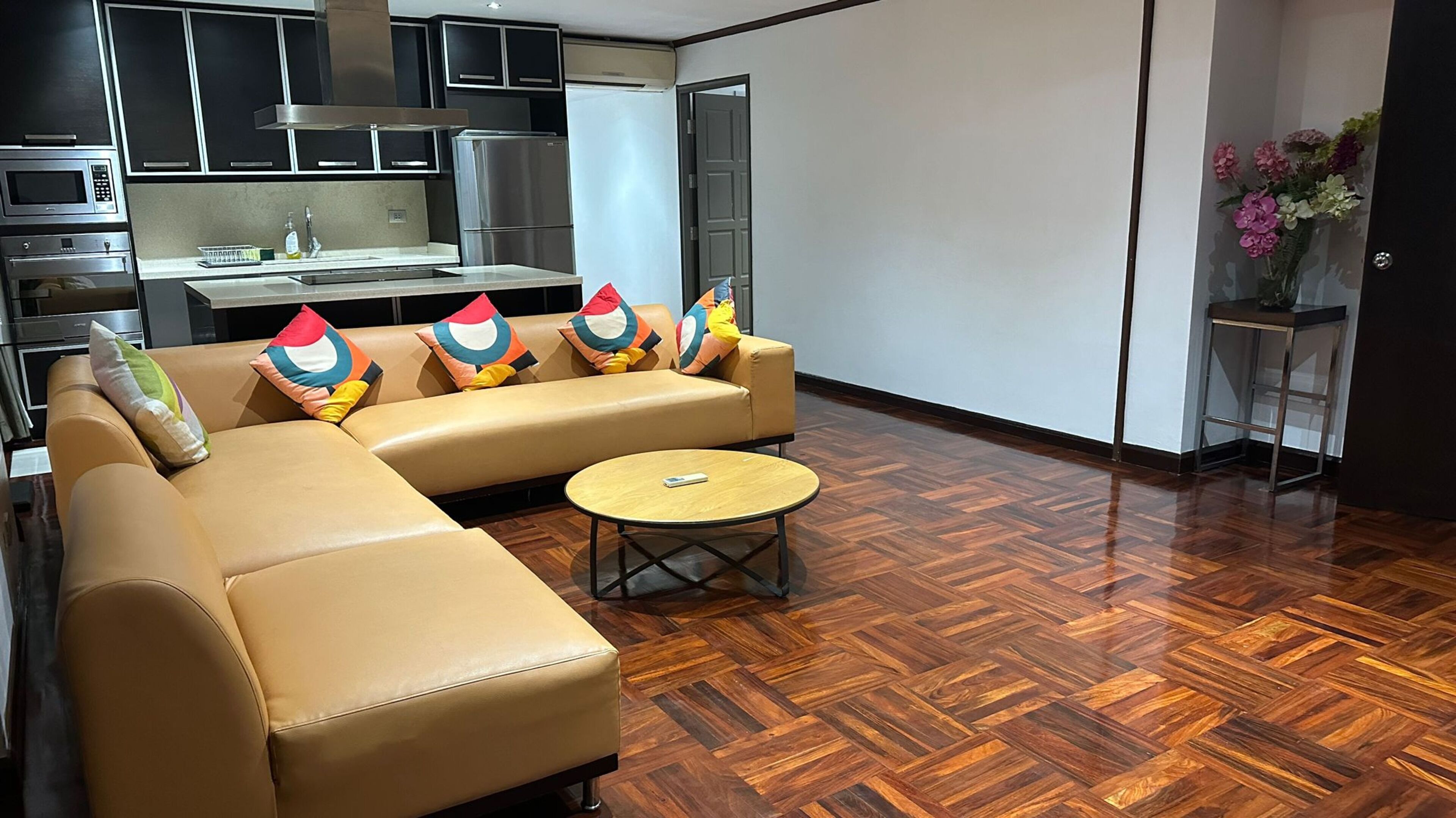A modern living room with a sofa, a coffee table, and a kitchen area in the background.