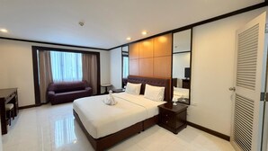 A hotel room with a large bed, a sofa, a desk, and a mirror. - Direct Rooms at Omni Complex Nana (Bangkok)