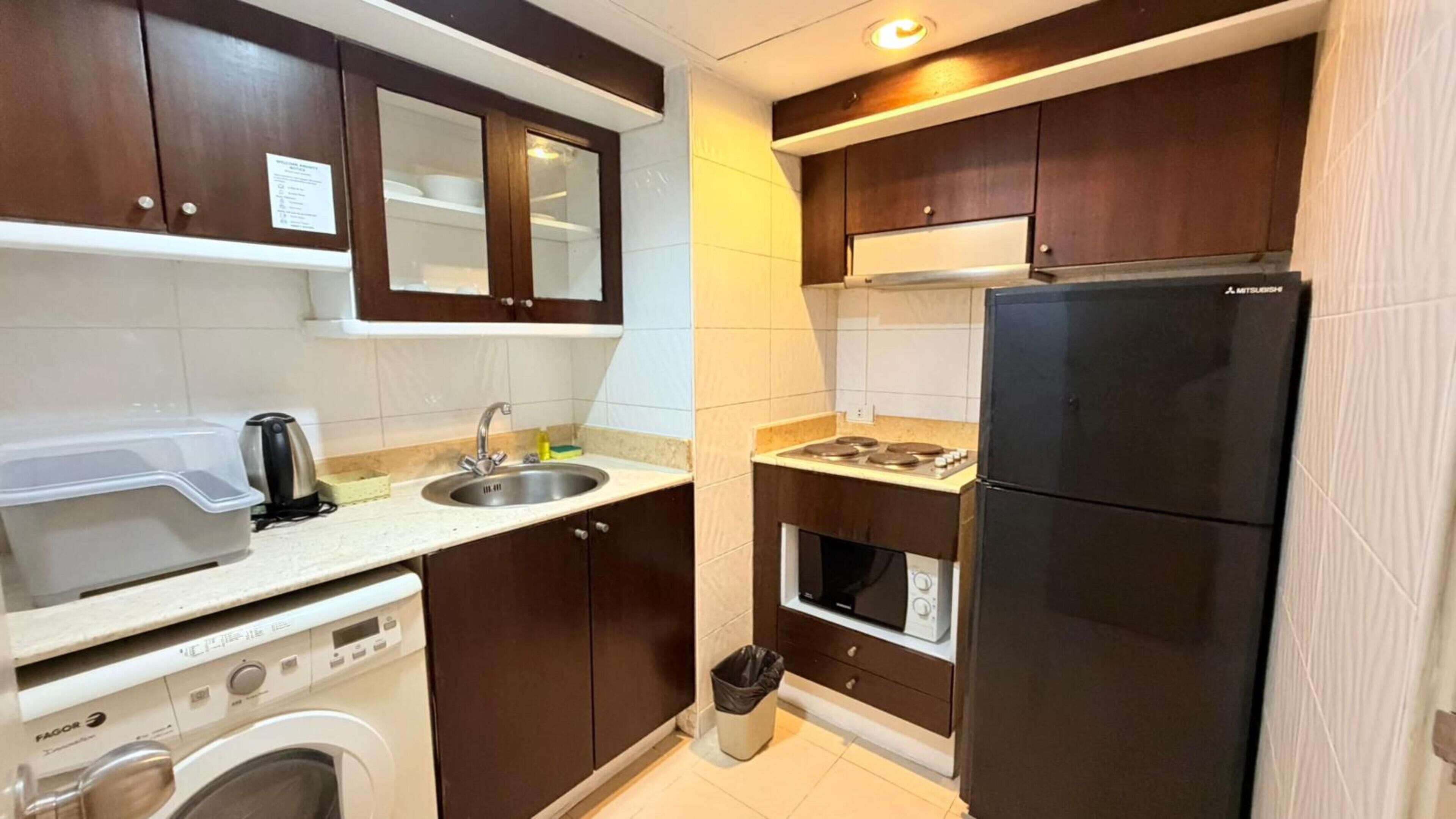 A compact kitchen with a washing machine, a sink, a stove, and a refrigerator.